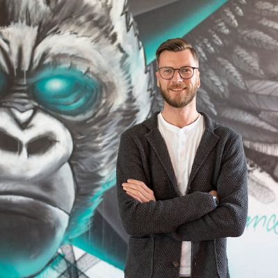 Mitarbeiter Andreas Nehrkorn vor Wand mit Affen